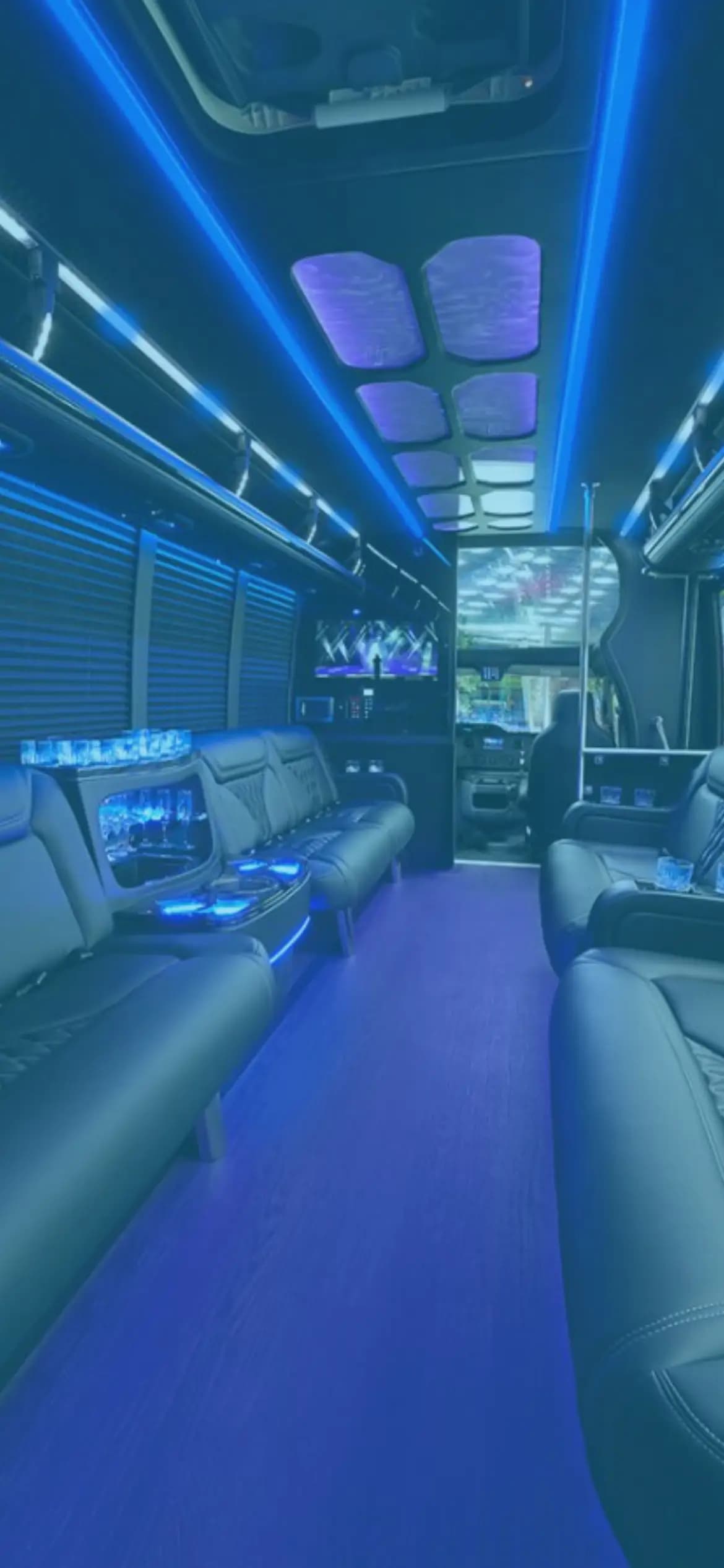 Interior of a Catch party bus, leather bench seating under blue LED lighting